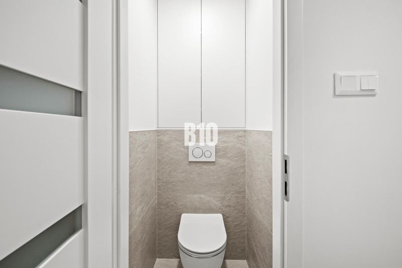 Toilette mit weißen Türen und Fliesen in einer 3-Zimmer-Wohnung.