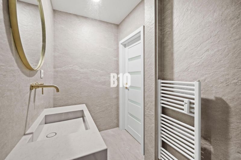 Badezimmer mit goldenem Spiegel und Waschbecken in einer 3-Zimmer-Wohnung, neutrale Töne.