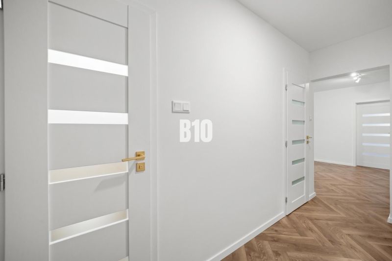 Weiße Inneneinrichtung einer 3-Zimmer-Wohnung mit Holzboden und eleganten Türen.