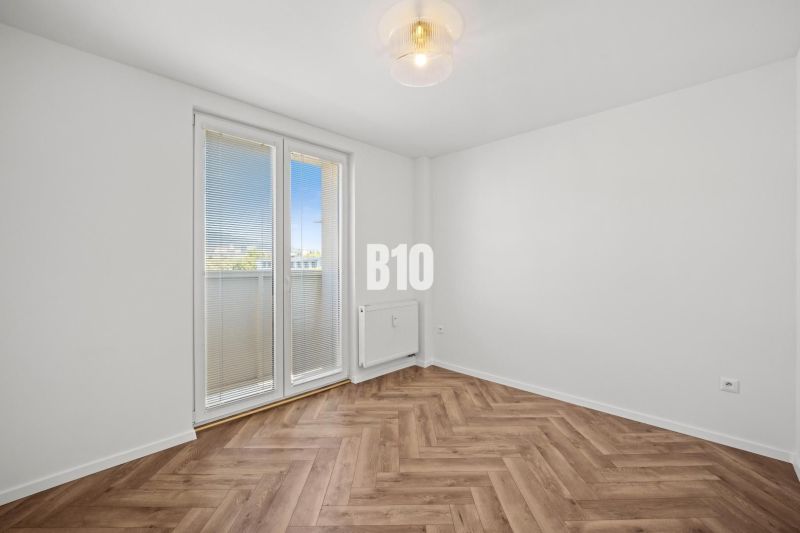 Ein leerer Raum mit Holzboden und Balkontüren in einer 3-Zimmer-Wohnung.