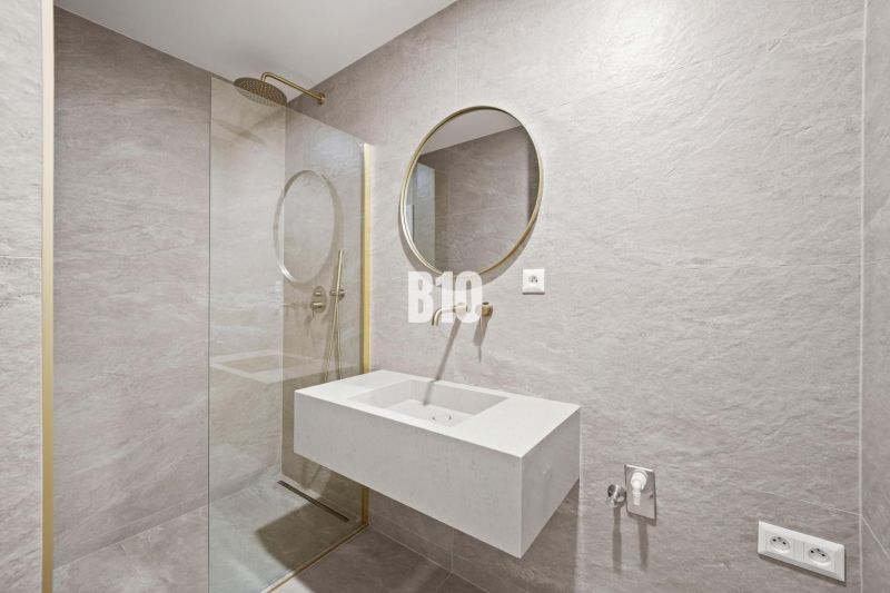 Badezimmer mit rundem Spiegel und Duschkabine in einer 3-Zimmer-Wohnung.