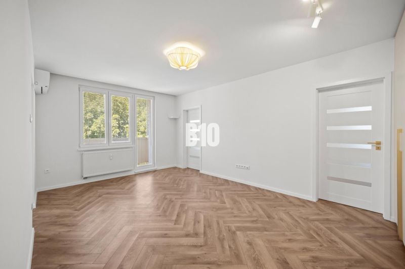 Ein geräumiger Raum mit einem Holzboden in einer 3-Zimmer-Wohnung.