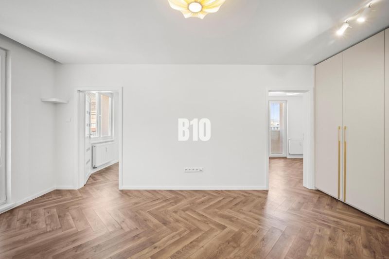 Ein Zimmer in einer 3-Zimmer-Wohnung mit einem Boden in Holzoptik und Einbauschränken.