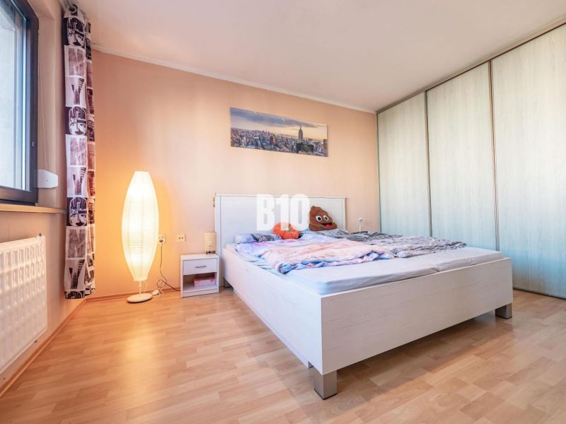 Schlafzimmer mit Holzboden, Bett und Schrank in einer Einzimmerwohnung.