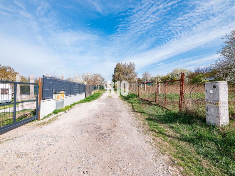 Weg zwischen Wohnbaugrundstücken in Nitra, zwischen dem Zaun und der grünen Vegetation.