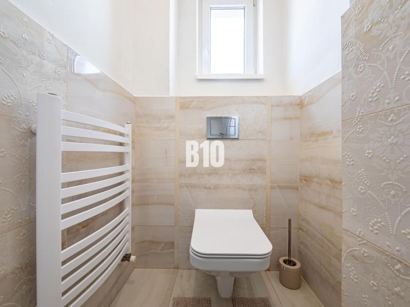 Das Badezimmer in einem Einfamilienhaus enthält ein hängendes WC, Fliesen und einen Heizkörper.