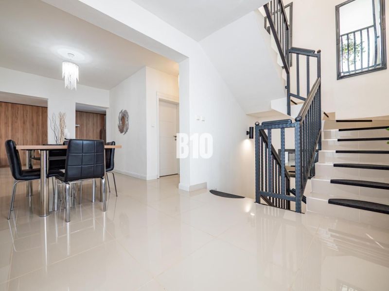 Innenraum eines Einfamilienhauses mit Esstisch und Treppe, Boden mit glänzender Oberfläche.