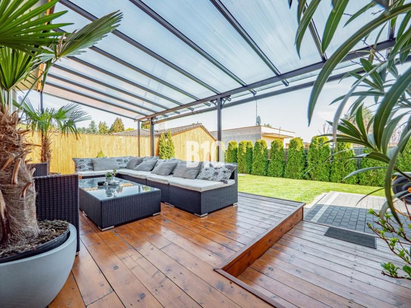 Ein Einfamilienhaus in Nitra mit überdachter Terrasse, Gartenmöbeln und einem Boden in Holzoptik.
