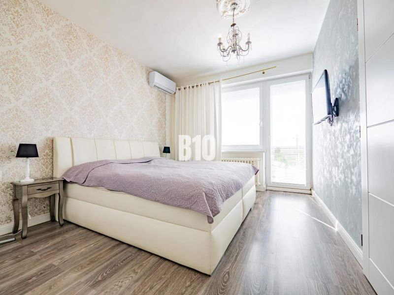 Schlafzimmer mit Bett, gemusterten Tapeten und Holzboden in einem Einfamilienhaus.