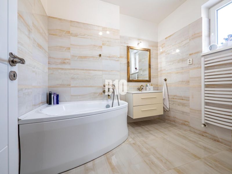 Luxuriöses Badezimmer mit Badewanne und Waschbecken in einem Einfamilienhaus, Boden mit Holzdekor.