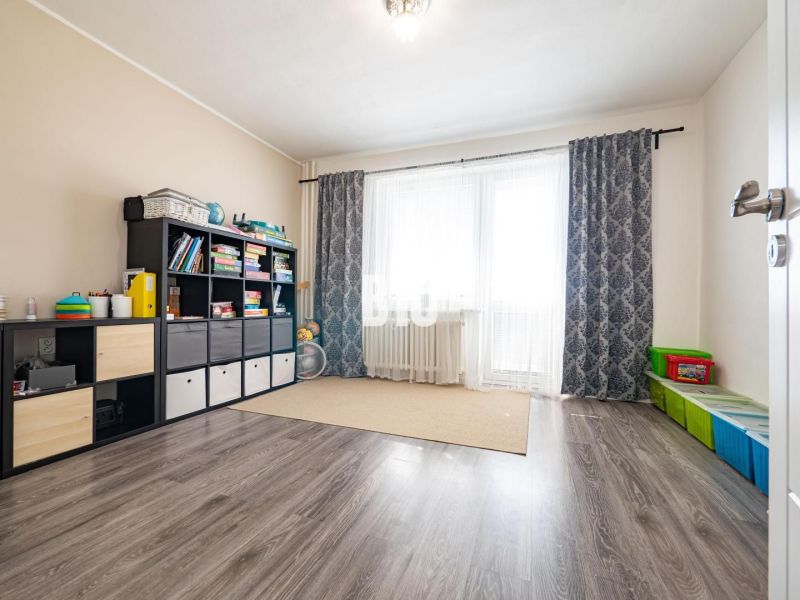 Ein Zimmer in einem Einfamilienhaus mit einem Boden in Holzoptik, einem Regal und Spielzeug.