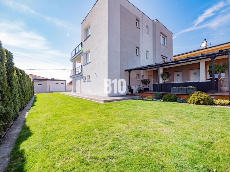 Ein Einfamilienhaus in Nitra mit einem geräumigen Garten und grünem Rasen.