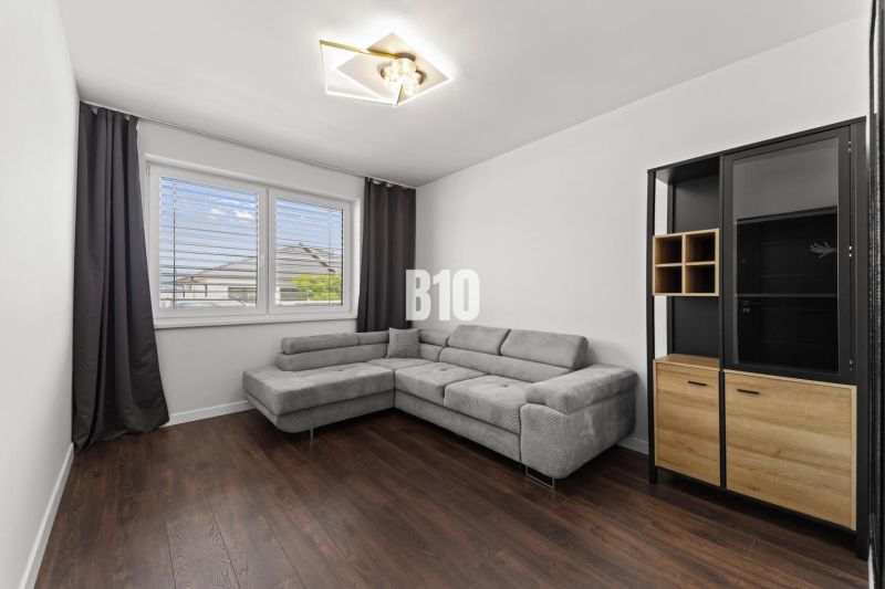 Wohnzimmer mit Ecksofa, Boden mit Holzdekor, Schrank.