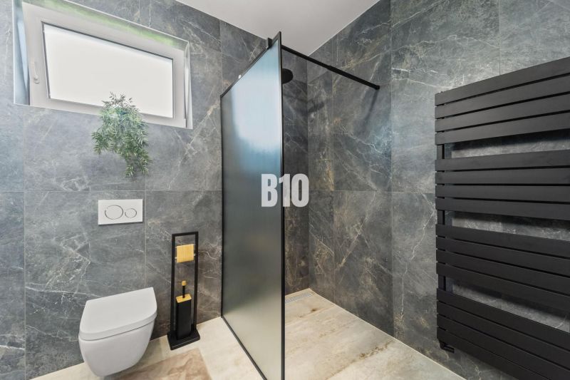 Badezimmer in einem Einfamilienhaus mit einem schwarzen Heizkörper und einer Duschkabine.