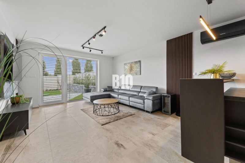 Wohnzimmer mit Ledersofa und Fenstern zur Terrasse in einem Einfamilienhaus.