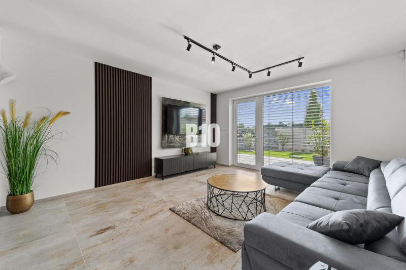 Wohnzimmer in einem Einfamilienhaus mit Sofa, Fernseher und Fenster mit Ausblick.