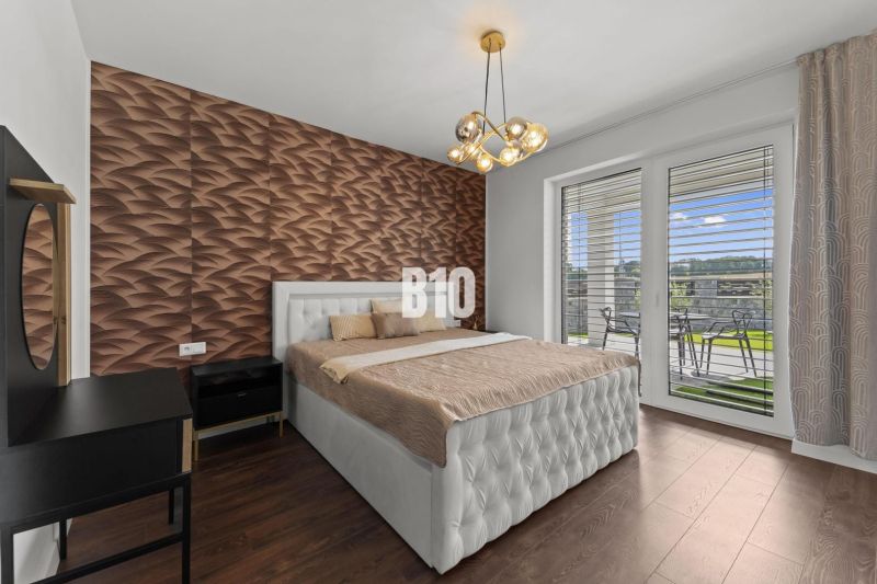 Schlafzimmer mit Holzboden, gestepptem Betthaupt und Blick auf die Terrasse.