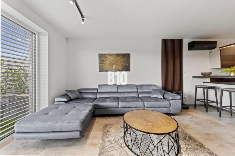 Graues Sofa, runder Tisch und Bild im Wohnzimmer eines Einfamilienhauses.