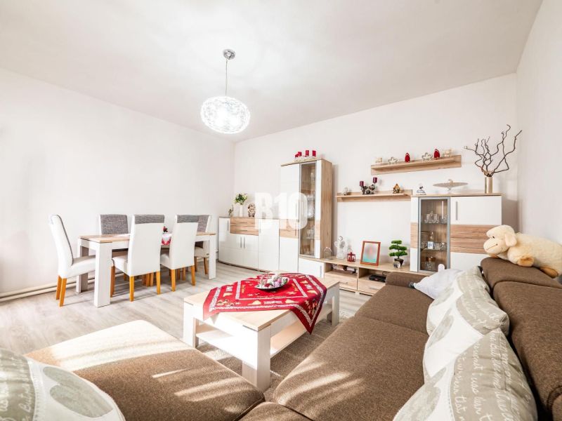 Wohnzimmer mit Esstisch, Holzboden und braunem Sofa in einem Einfamilienhaus.