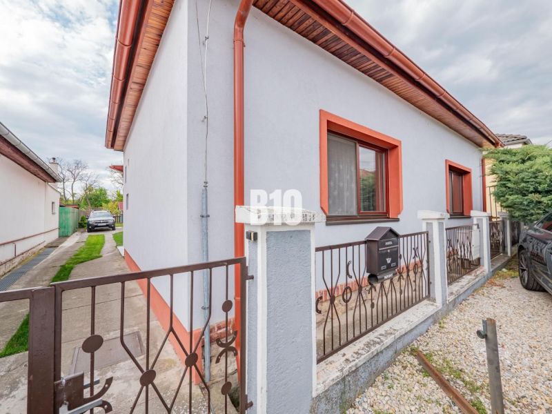 Ein Einfamilienhaus in Nitra mit weißer Fassade, roter Umrandung und einem Garten.