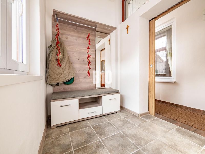 Eingangshalle in einem Einfamilienhaus mit Garderobe, Sitzgelegenheit und Fliesenboden.