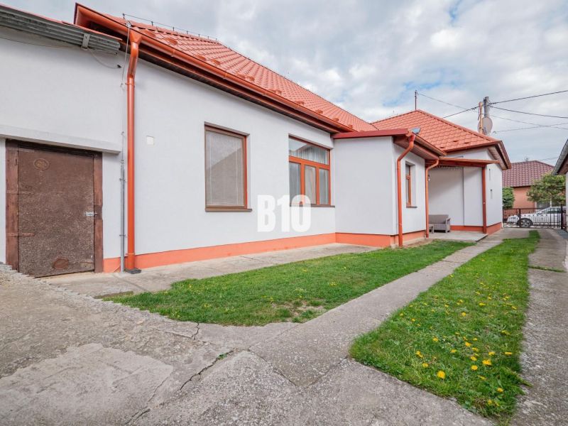 Ein Einfamilienhaus in Nitra mit rotem Dach, Hof und einfacher Gartengestaltung.
