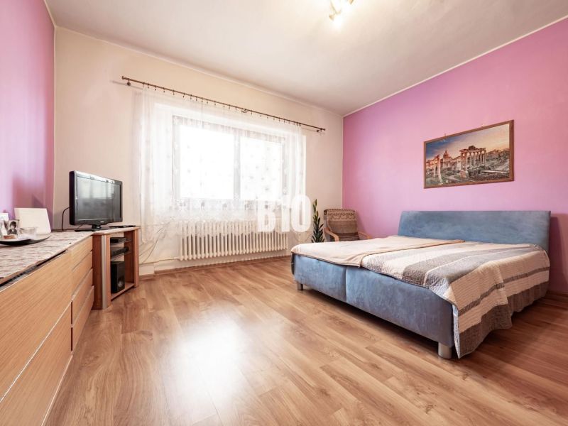 Schlafzimmer im Einfamilienhaus mit Holzboden, Möbeln und Fernseher.