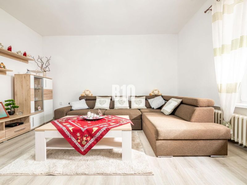 Wohnzimmer in einem Einfamilienhaus mit Ecksofa, Holzdekor und bunten Tischsets.