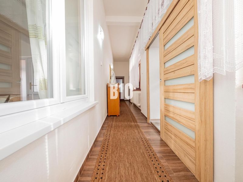 Ein Flur in einem Einfamilienhaus mit einem Boden in Holzoptik und Schiebetüren.