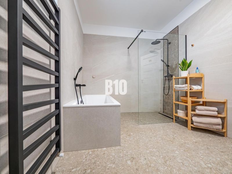 Ein Badezimmer in einem Einfamilienhaus mit Badewanne, Dusche und einem Regal für Handtücher.