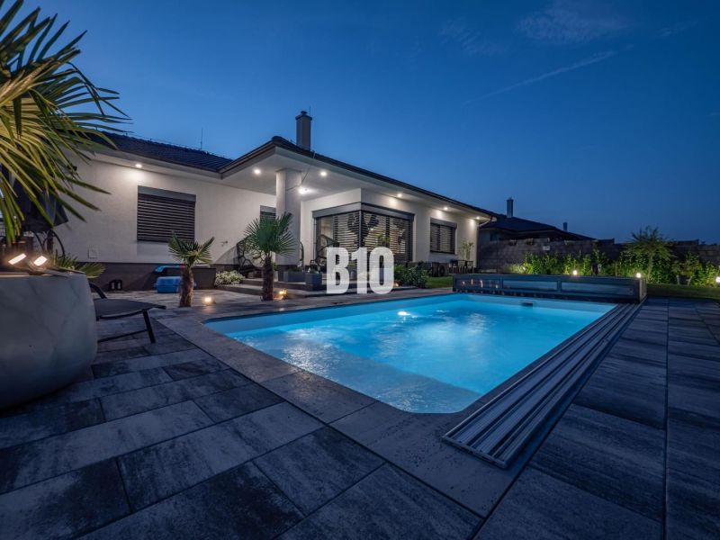 Ein Einfamilienhaus in Nitra mit Pool und Gartenmöbeln in abendlicher Atmosphäre.