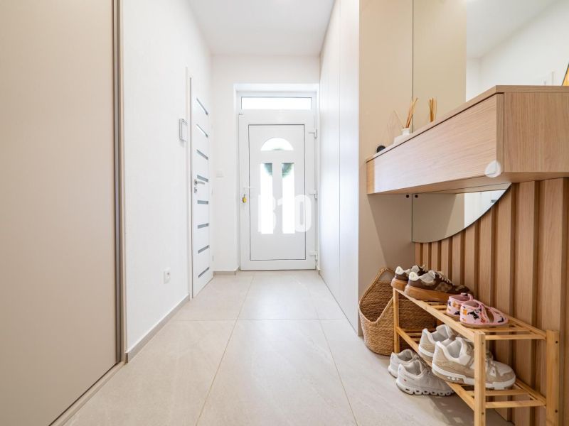 Interieur eines Einfamilienhauses mit einem hellen Flur, einem Schuhschrank und einem Spiegel.