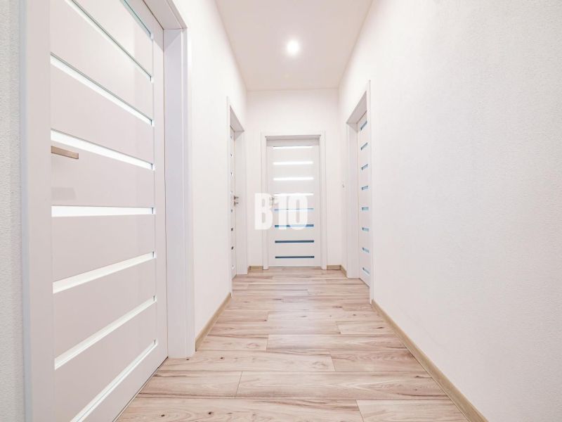 Ein heller Flur in einem Einfamilienhaus mit einem Boden in Holzoptik und weißen Türen.
