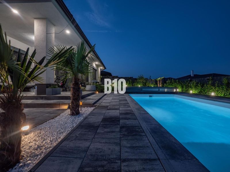 Ein Einfamilienhaus in Nitra mit einem Pool und einem beleuchteten Garten am Abend.