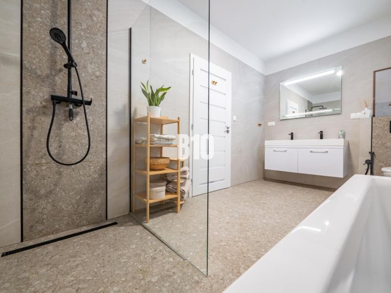 Ein Badezimmer mit einer modernen Dusche und einer Badewanne in einem Einfamilienhaus.