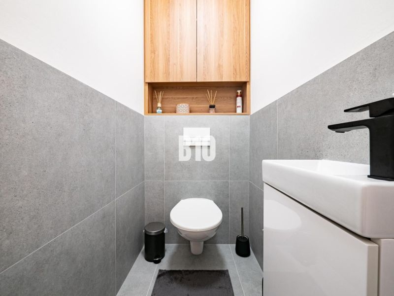 Ein Badezimmer in einem Einfamilienhaus mit grauen Fliesen und schlichtem Design.