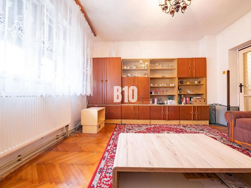 Wohnzimmer mit übersichtlicher Vitrine, Holzboden und rotem Teppich in einem Einfamilienhaus.