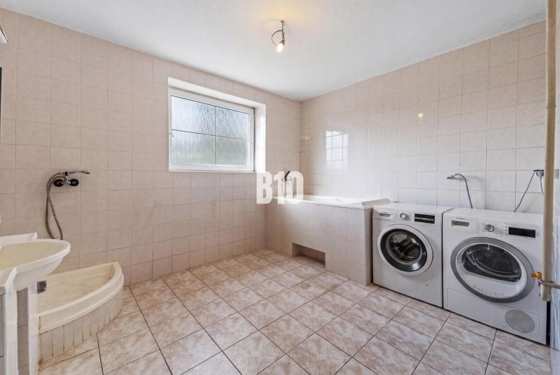 Badezimmer im Einfamilienhaus mit Waschmaschine, Badewanne und Dusche.