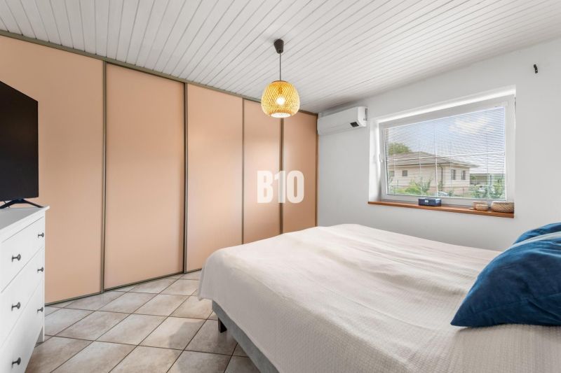 Schlafzimmer im Einfamilienhaus mit großem Einbauschrank, Klimaanlage und Fenster.