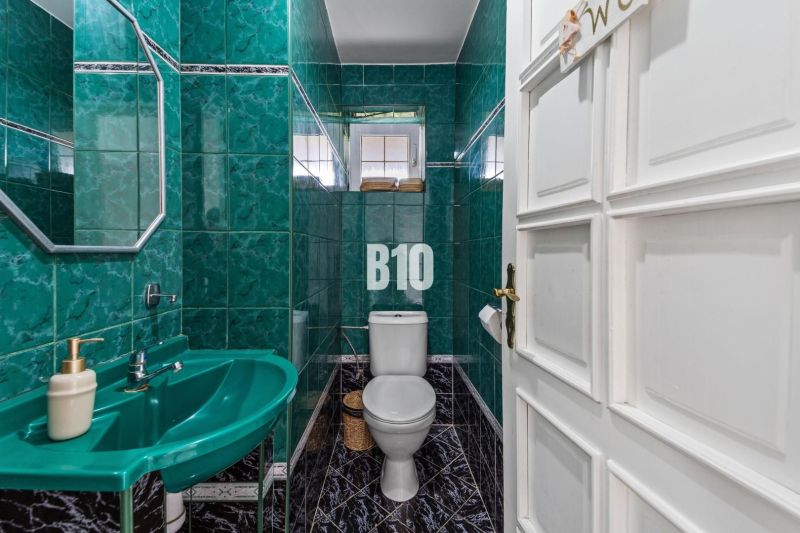 Badezimmer in einem Einfamilienhaus mit grünen Fliesen und Waschbecken.