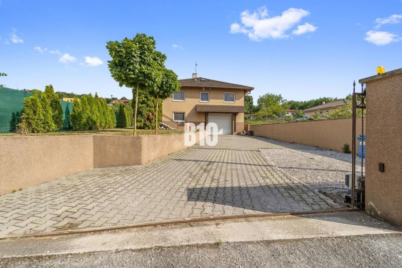 Ein Einfamilienhaus in Nitra mit gepflasterter Zufahrt und gepflegtem Garten.