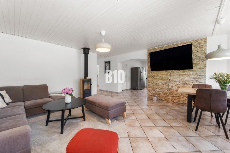 Wohnzimmer in einem Einfamilienhaus mit Kamin und Fernseher an einer mit Stein verkleideten Wand.