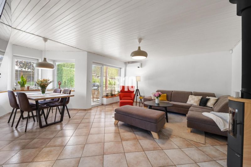 Ein geräumiges Wohnzimmer in einem Einfamilienhaus mit einem Esstisch und einem bequemen Sofa.
