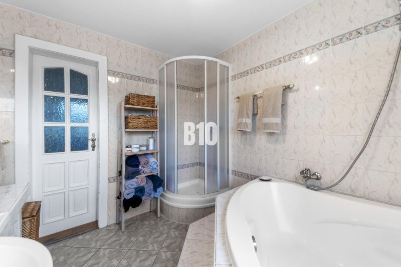 Badezimmer im Einfamilienhaus mit Badewanne, Dusche und Handtuchregal.