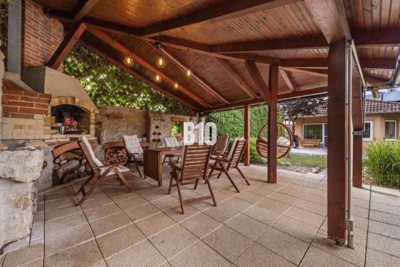 Überdachte Terrasse mit Kamin und Holzstühlen bei einem Einfamilienhaus in Nitra.