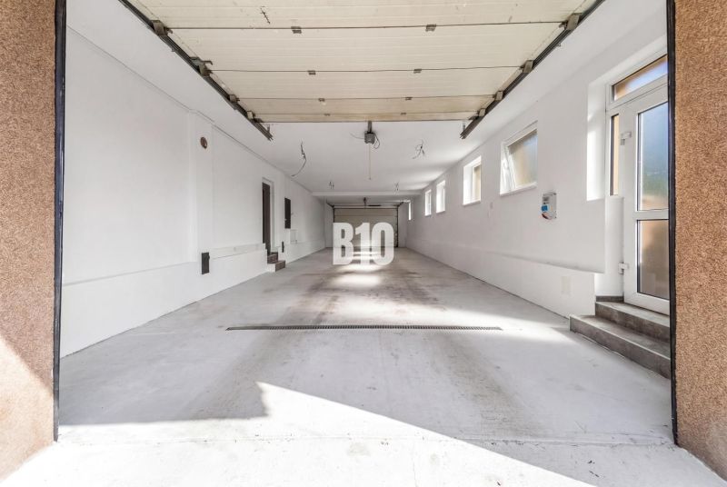 Eine geräumige Garage in einem Einfamilienhaus in der Stadt Nitra mit mehreren Fenstern und weißen Wänden.