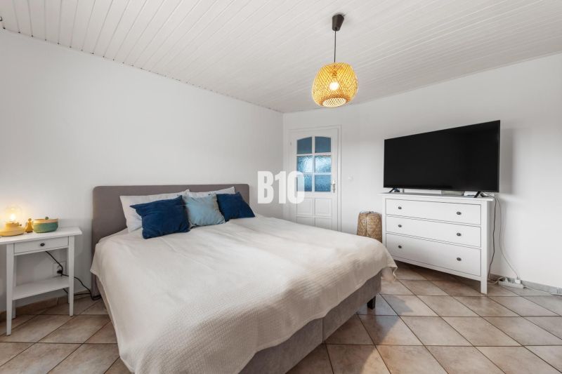 Schlafzimmer im Einfamilienhaus mit Bett, Fernseher und Nachttisch.