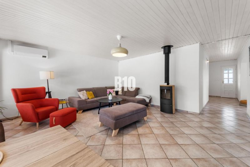 Wohnzimmer in einem Einfamilienhaus mit Kamin, rotem Sessel und grauem Sofa.