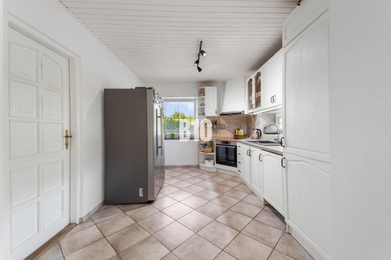 Küche mit weißen Schränken und Geräten in einem Einfamilienhaus.