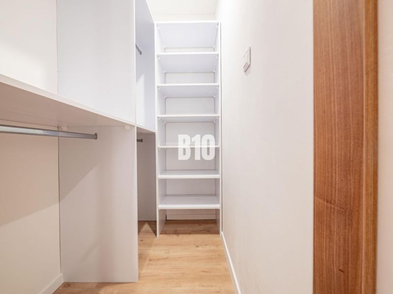 Ein Kleiderschrank in einer 3-Zimmer-Wohnung mit Regalen und einem Boden in Holzoptik.